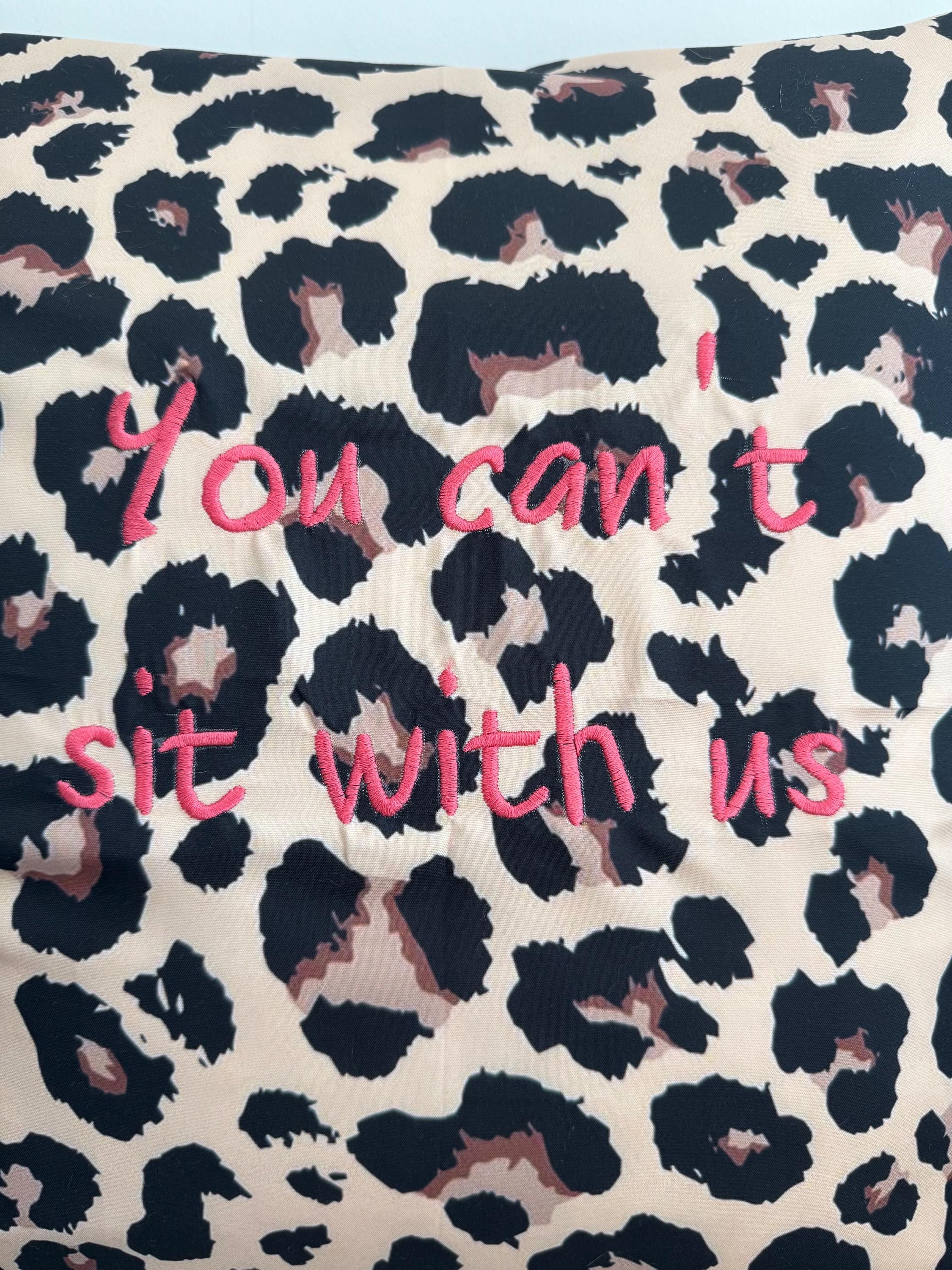 Leopard print cushion cover, you can’t sit with us logo embroidered in pink.